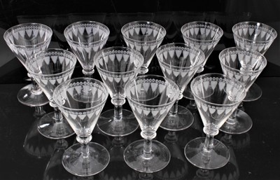 Lot 122 - Good set of twelve 19th century wine glasses, the bowls etched with a feather and circle pattern, on plain collared stems and conical feet, 12cm high