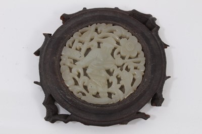 Lot 765 - Chinese jade plaque, carved and pierced with a fisherman and scrolling foliage, in a wooden mount, 8cm across