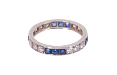 Lot 514 - Diamond and sapphire full band eternity ring with a trio of brilliant cut diamonds alternating with calibre cut blue sapphires. Ring size L.