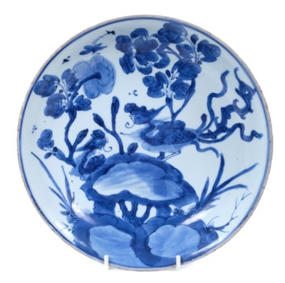 Lot 134 - Chinese blue and white porcleain dish, Kangxi period, decorated with a phoenix perched on rockwork, surrounded by flowers, double ring mark to base, 22cm diameter