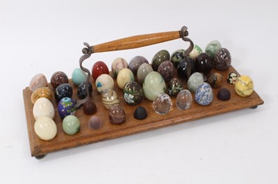 Lot 832 - Collection of miniature carved stone and other specimen eggs, housed on wooden stand, approximately 50