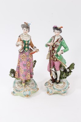 Lot 196 - A pair of Chelsea/Derby bocage figures of huntsman and companion, circa 1765, modelled standing holding gun and powder flask respectively, on gilt and blue enamelled scrollwork bases, gold anchor m...