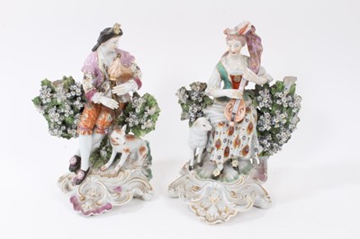Lot 198 - Pair of Derby figures of musicians, with a dog and sheep by their sides, seated within floral encrusted bocage, on gilt and pink enamelled scrollwork bases, 22.5cm and 23cm high