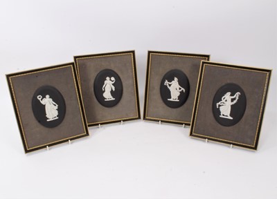 Lot 261 - Set of four Wedgwood 'basalt' jasperware plaques, of oval shape, decorated in the classical style with female figures, in Hogarth frames, the plaques measuring 13cm x 9.5cm