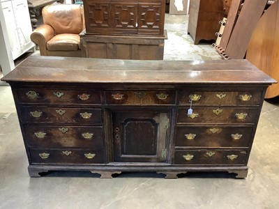 Lot 1491 - 18th century and later oak dresser base,with central fielded panel cupboard and nine drawers, raised on cabriole legs, 195cm wide x 58cm deep x 90cm high