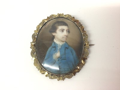 Lot 82 - 18th century oval portrait miniature on ivory of a young man wearing a blue overcoat, in a later 19th century yellow metal brooch mount, portrait 44mm x 36mm