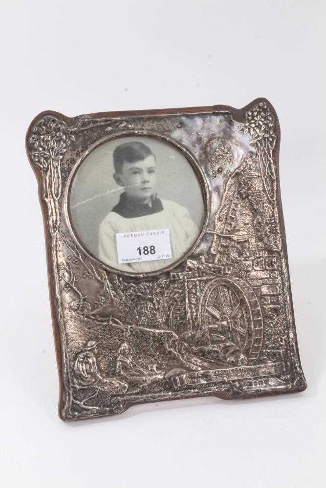 Lot 188 - Unusual Edwardian Arts & Crafts silver photograph frame with raised decoration depicting a watermill, captioned 'More water glideth by the mill than wots the miller of''