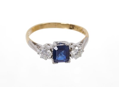 Lot 584 - Sapphire and diamond three stone ring with a rectangular step cut blue sapphire flanked  by two round brilliant cut diamonds in platinum claw setting on 18ct yellow gold shank