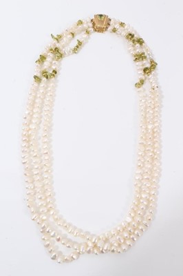 Lot 215 - Three strand fresh water pearl necklace, interspaced with raw peridot beads, on 18ct gold clasp set with a further oval mixed cut peridot. 44cm long