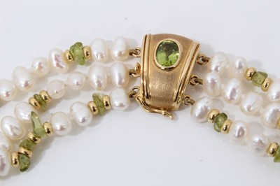 Lot 215 - Three strand fresh water pearl necklace, interspaced with raw peridot beads, on 18ct gold clasp set with a further oval mixed cut peridot. 44cm long