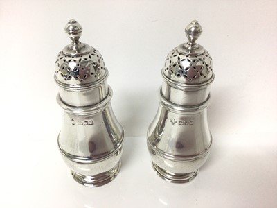 Lot 124 - George V silver salt and pepper, of baluster form, with reeded decoration and pierced tops, hallmarked for London 1915, together with a pair of cased silver-mounted cut glass salts with silver spoo...