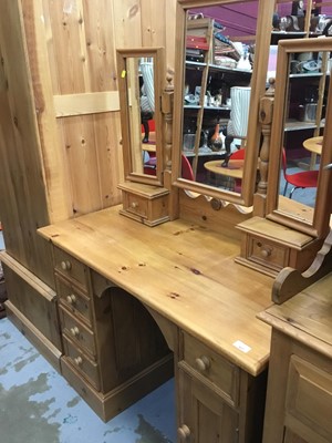 Lot 927 - Contemporary pine dressing table with triple mirror back, kneehole with cupboard and drawers 106 cm wide and pine bedside cupboard(2)