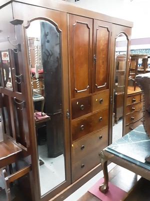 Lot 957 - Early 20th century mahogany triple wardrobe, the centre section with two panelled doors, two short and three long drawers below flanked by an arched bevelled mirror door to each side, 182.5cm wide,...